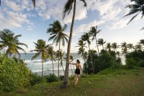 Tranquila viajera femenina entre palmeras a orillas del mar - foto de stock