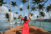 Tranquilo viajante feminino entre as palmas das mãos na praia — Fotografia de Stock