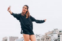 Zufriedene junge Frau in Freizeitkleidung macht Selfie auf der Straße — Stockfoto