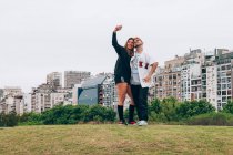 Amigos sonriendo mientras hacen selfie en el teléfono inteligente en la ciudad - foto de stock