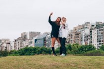 Amigos sonriendo mientras hacen selfie en el teléfono inteligente en la ciudad - foto de stock