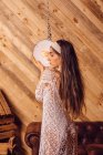 Jovem posando entre lâmpadas de teto no fundo de madeira — Fotografia de Stock