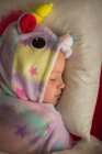 Девушка в пижаме единорога спит в постели дома — стоковое фото