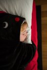 Petit garçon en pyjama kigurumi noir dormant au lit — Photo de stock