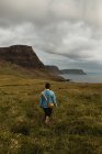 Sereno turista disfrutando de la vista del tranquilo valle verde en un clima nublado en Escocia - foto de stock