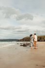 Pareja feliz caminando y abrazando en la costa arenosa escocesa - foto de stock