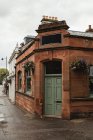 Edificio de ladrillo rojo vintage con puerta verde y espacio vacío para letrero de tienda decorado con flores en la calle de Escocia - foto de stock