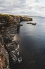 Скалистое побережье среди спокойной морской воды в солнечное время дня в Шотландии — стоковое фото
