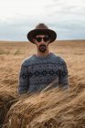Человек, стоящий на сухом поле и смотрящий в камеру в Шотландии — стоковое фото