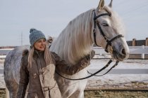 Тепло одягнена жінка з сірим конем надворі — стокове фото