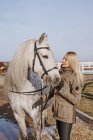 Теплая женщина с серой лошадью снаружи — стоковое фото