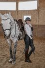 Всадница, стоящая с серой лошадью на круглой арене — стоковое фото