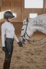 Cavaleiro ajustando freio no cavalo cinza maçã na arena redonda — Fotografia de Stock