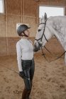 Rider adjusting bridle at dapple gray horse in round arena — Stock Photo