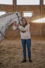 Женщина с серой лошадью с длинным пушистым хвостом ходит по большой арене — стоковое фото