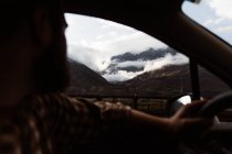 Montagne potenti e cielo nuvoloso vista dal finestrino della macchina — Foto stock