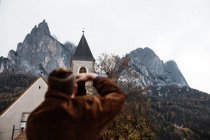 Hombre viajero haciendo foto de la naturaleza y la iglesia en la cámara - foto de stock