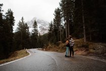 Casual resting couple standing in an embrace on route amid forest — Stock Photo
