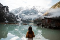 Mujer descansando en ropa casual deleitándose con vistas cerca del lago y las montañas - foto de stock