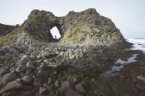 Бічний вид на самицю в теплому одязі, що стоїть на краю скелі в печері в гавані Північної Ірландії, дивлячись у море. — стокове фото