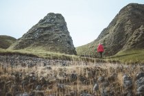 Mulher anônima desfrutando paisagem cênica incrível da Irlanda do Norte durante a viagem enquanto caminhava em solo rochoso — Fotografia de Stock