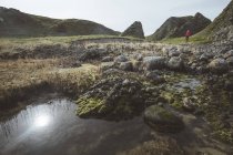 Donna anonima godendo incredibile paesaggio panoramico dell'Irlanda del Nord durante il viaggio mentre si cammina vicino al fiume poco profondo che scorre verso le acque della riva rocciosa — Foto stock