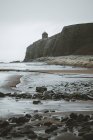 Scenic landscape with Mussenden Temple located on stone cliff at Northern Ireland coastline and stormy sea waves dashing against rocks with grey cloudy sky in background — Stock Photo