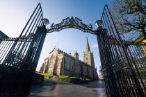 Von unten der St. Columbs Kathedrale durch ein offenes eisernes Eingangstor mit Gittern und dekorativen Elementen vor blauem Himmel an einem sonnigen Frühlingstag in Derry Nordirland — Stockfoto