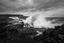 Meereswellen krachen auf Felsen und brechen an stürmischen Tagen mit dichten Wolken an der nordirischen Küste zu Spritzern zusammen — Stockfoto
