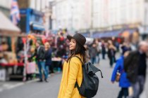 Femme en manteau jaune et chapeau élégant marchant sur la route pendant le carnaval à Londres, Royaume-Uni — Photo de stock