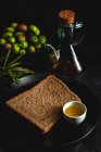 Fresh Spanish extra virgin olive oil with olives and old olive branch on dark background Healthy food Mediterranean diet. Vegan. Vegetarian. Toasted bread — Stock Photo