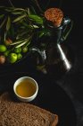 Aceite de oliva virgen extra español fresco con aceitunas y rama de olivo vieja sobre fondo oscuro Alimentación saludable Dieta mediterránea. Vegano. Vegetariano - foto de stock