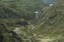 Chemin vers l'eau calme à travers la vallée avec herbe sèche et verte entourée de montagnes au Chili — Photo de stock