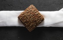 Pane biologico granuloso con semi su asciugamano bianco — Foto stock