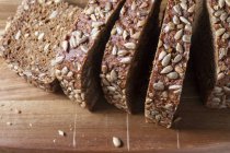 Нарізаний хліб з насінням на дерев'яній обробній дошці — стокове фото