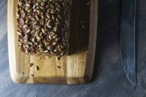Pan integral en rodajas con semillas en tabla de cortar de madera - foto de stock