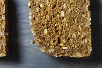 Pane biologico affettato con semi su fondo di legno — Foto stock