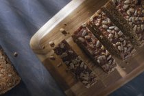Pão integral fatiado com sementes em tábua de corte de madeira — Fotografia de Stock