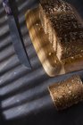 Scheiben Vollkornbrot auf Holzschneidebrett und Küchenmesser auf Holztisch — Stockfoto