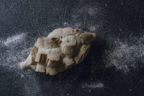 Vue du dessus du pain artisanal frais croustillant avec diverses incisions sur fond gris saupoudré de farine blanche — Photo de stock