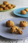 Frische braune Kekse mit Krümeln auf bunten Keramiktellern auf dem Tisch in der Küche — Stockfoto