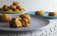 Frische braune Kekse mit Krümeln auf bunten Keramiktellern auf dem Tisch in der Küche — Stockfoto