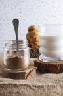 Composición de galletas orgánicas caseras con tarro de cacao en polvo y vaso de sabrosa leche - foto de stock
