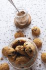 Gustosi biscotti marroni e barattolo trasparente di cacao in polvere sul tavolo — Foto stock