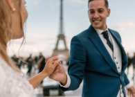 Brilho em terno azul e noiva em vestido de casamento branco tendo dança lenta sorrindo e olhando um para o outro com Torre Eiffel no fundo em Paris — Fotografia de Stock