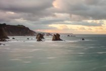 Pictuosas y majestuosas aguas de la bahía rompiendo rocas en la playa de Silence O Gaviero en España. - foto de stock