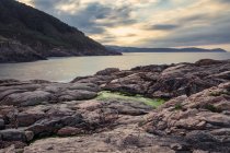 Foggy superficie del mare con grandi rocce sulla spiaggia sabbiosa e montagne all'alba sulla spiaggia di Portonovo in Italia — Foto stock