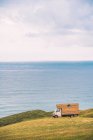 Золоте поле на пагорбі і маленький вантажний автомобіль з блакитним морем і хмарним небом на тлі Comillas Cantabria в Іспанії — стокове фото