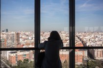 Анонимная женщина смотрит в окно балкона — стоковое фото