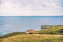 Campo dourado na colina e pequeno caminhão de carga com mar azul e céu nublado no fundo em Comillas Cantabria em Espanha — Fotografia de Stock